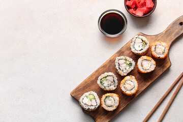Tasty sushi rolls, soy sauce and ginger on light background