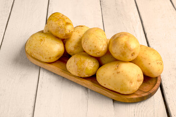Tray with raw baby potatoes on white wooden background