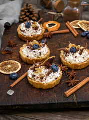 sweet cakes with white cream and chocolate powder on a brown wooden board, close up