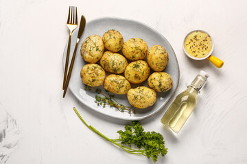 Plate of boiled baby potatoes with dill and sauce on white background