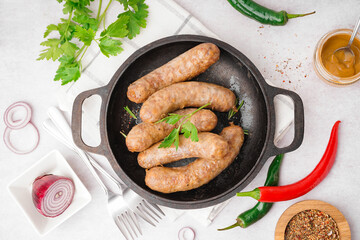 Frying pan of tasty homemade sausages on light background
