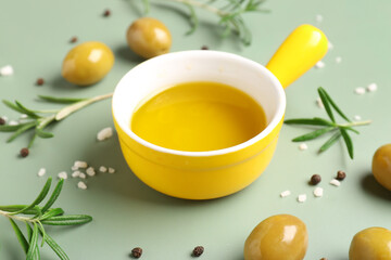 Bowl with fresh olive oil on green background
