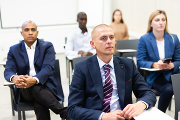 Group of people attentively listening sitting in boardroom