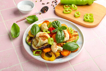 Plate of grilled vegetables on pink tile background