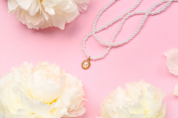 Composition with beautiful female necklace and white peony flowers on pink background
