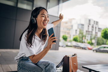 Fototapeta premium Young Japanese woman listening to music on smart phone and singing