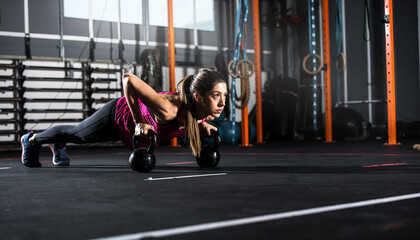 Determined athletic girl works out at the gym with a kettlebell