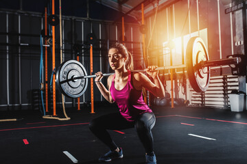 Fototapeta na wymiar Determined athletic girl works out at the gym with a barbell