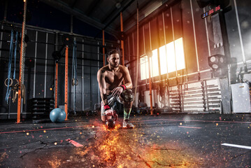 Obraz na płótnie Canvas Determined athletic boy works out at the gym with a fiery kettlebell