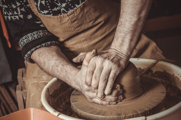 Adult male potter master mashing the clay.