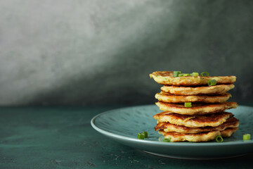 Plate with tasty zucchini fritters on table