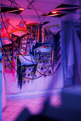 Fototapeta na wymiar Deserted urban space with purple and pink neon lights, showing dust on walls, abandoned warehouse with crumbling structure covered in messy graffiti paint. Place with fluorescent lights.
