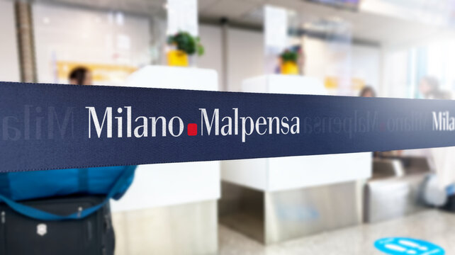 Milan, Italy, June 21 2023: Blue retractable belt barrier with white Milano Malpensa Airport logo