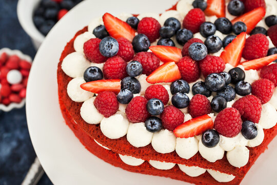 Delicious homemade heart shaped red velvet cake decorated with cream and fresh berries