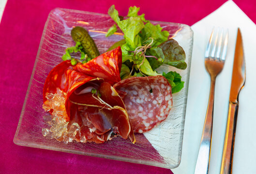 Delicious smoked assorted meat of dried sausage and sliced carbonade, served with pickled gherkins and lettuce leaves