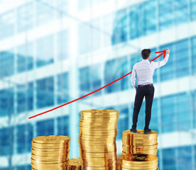 Businessman draws red growing arrow of company statistics over a pile of money