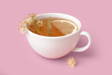Cup of linden tea with lemon on pink background