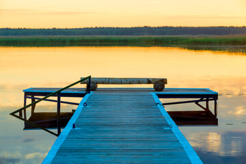 view of a wooden pier near a picturesque calm lake at dawn