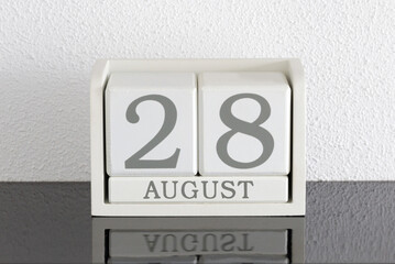 White block calendar present date 28 and month August on white wall background
