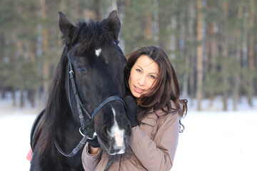 Portrait of a young black hair woman hugging a horse, close up