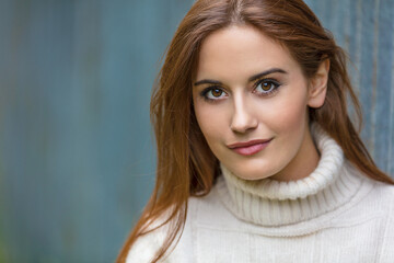Naklejka premium Outdoor portrait of beautiful girl or young woman with red hair wearing a white jumper