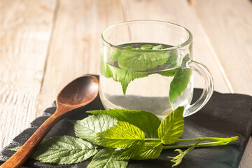 cup of tea from and green raspberry leaves on a wooden background. Blur and selective focus....