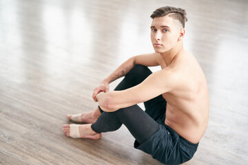 Fototapeta na wymiar Handsome ballet dancer sitting on the floor and resting after training.