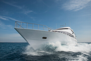 A luxury private motor yacht under way on tropical sea with bow wave