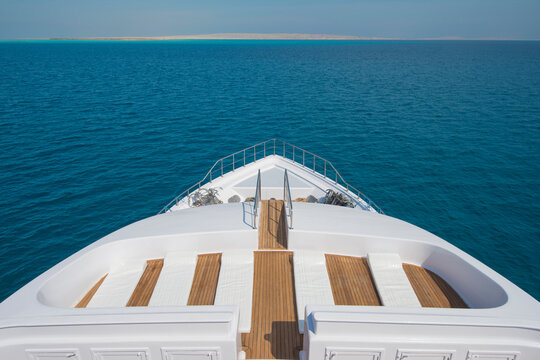 View over the bow of a large luxury motor yacht on tropical open ocean with sun beds © Designpics