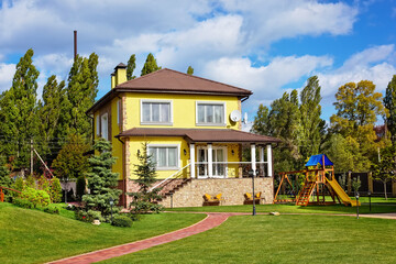 Fototapeta na wymiar Exterior of beautiful house with green loan and children playground