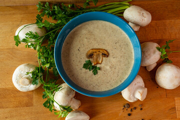 Mushroom soup with champignon mushrooms and parsley on wooden background