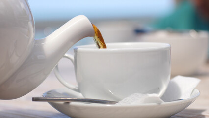 White teapot pouring tea into cup