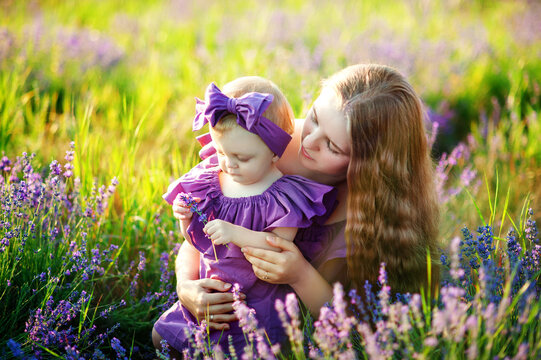 Beautiful young mother and her daughter having fun at the lavender field. Mothers Day