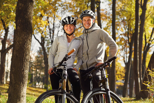 Young couple with the bicycle standing in the park in sunny autumn day.