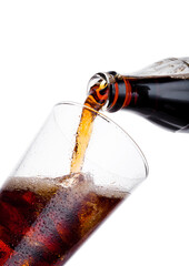 Pouring cola soda drink from bottle to glass  with ice cubes on white background