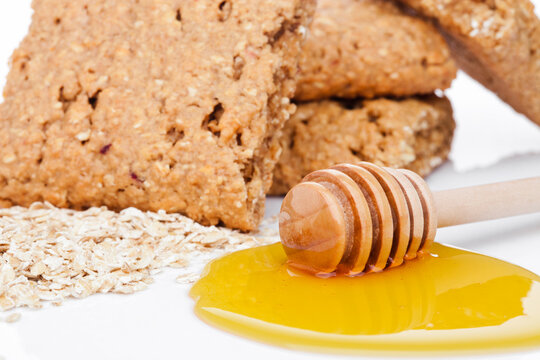 Healthy bio breakfast grain biscuits with honey and raw oat porridge on white background