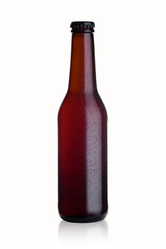Brown glass stout beer bottle with black cap isolated on white background with reflection and dew