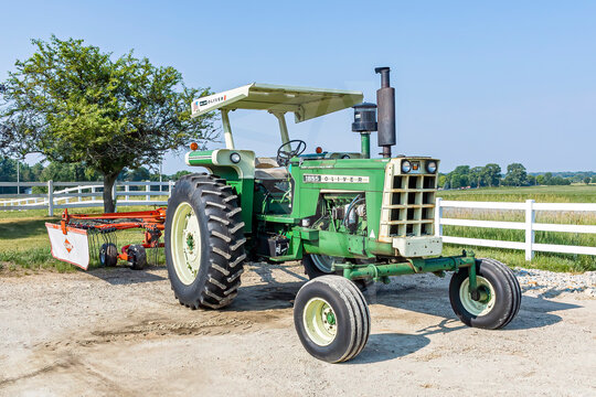 An 1855 Oliver tractor with a sunshade pulling to a Kuhn hay rake.