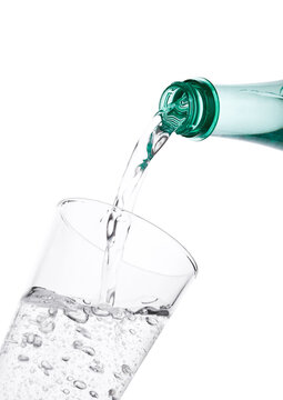 Pouring sparkling mineral water from bottle to glass on white background