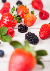 Freash organic healthy strawberries and rasppberries and blackberries on wood background