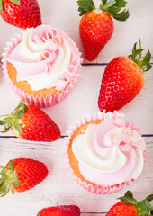 Cupcake muffin with strawberry cream dessert on wooden background with fresh strawberries