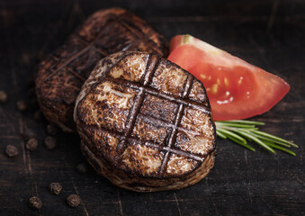 Grilled juicy beef pork steak slice on wooden background with pepper and rosemarine herb