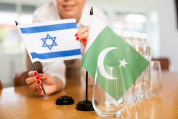 Little flag of Pakistan on table with bottles of water and flag of Israel put next to it by...
