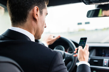 Man texting on his phone while driving by car - obrazy, fototapety, plakaty