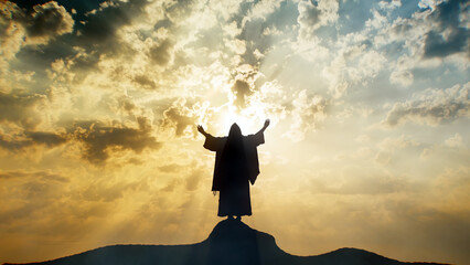 Silhouette of Jesus praying on a mount with sun rays and mystic clouds behind Him. - obrazy, fototapety, plakaty
