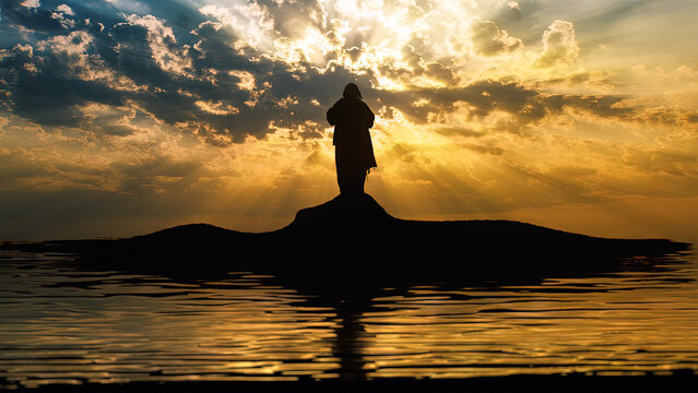 Silhouette of Jesus standing on a shore with water reflections and sun rays.