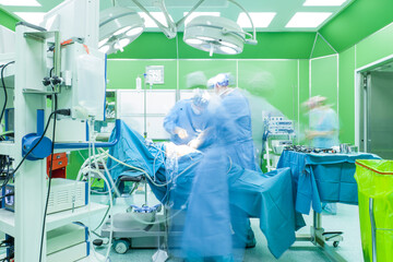 Team of doctors, motion blurred figures, are performing surgery in modern hospital.