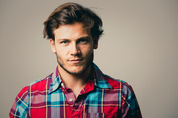 Fashion portrait of a handsome man with trendy hairstyle in a stylish shirt on light green background