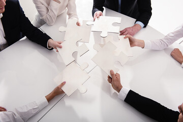 Businessmen working together to build a colored puzzle. Concept of teamwork, partnership,...