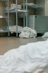 industrial laundry in a hotel dirty bed linen lies on the floor sorted before being loaded into the...